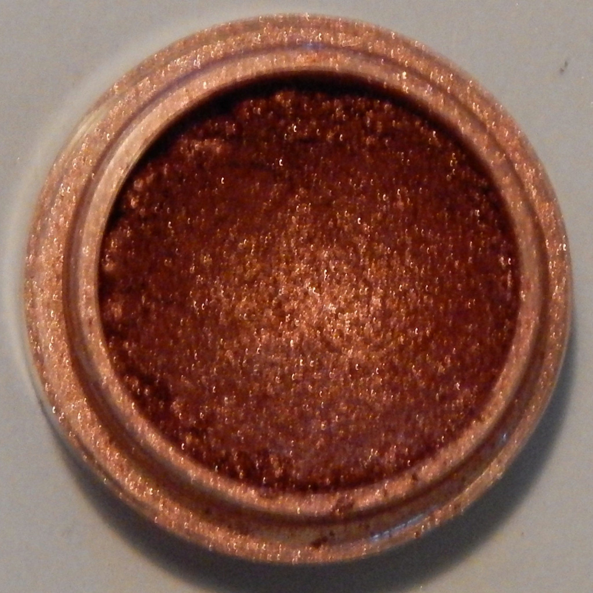 Side view of Fiesta Mineral Eyeshadow pot showing vibrant orange-gold shimmer and compact size