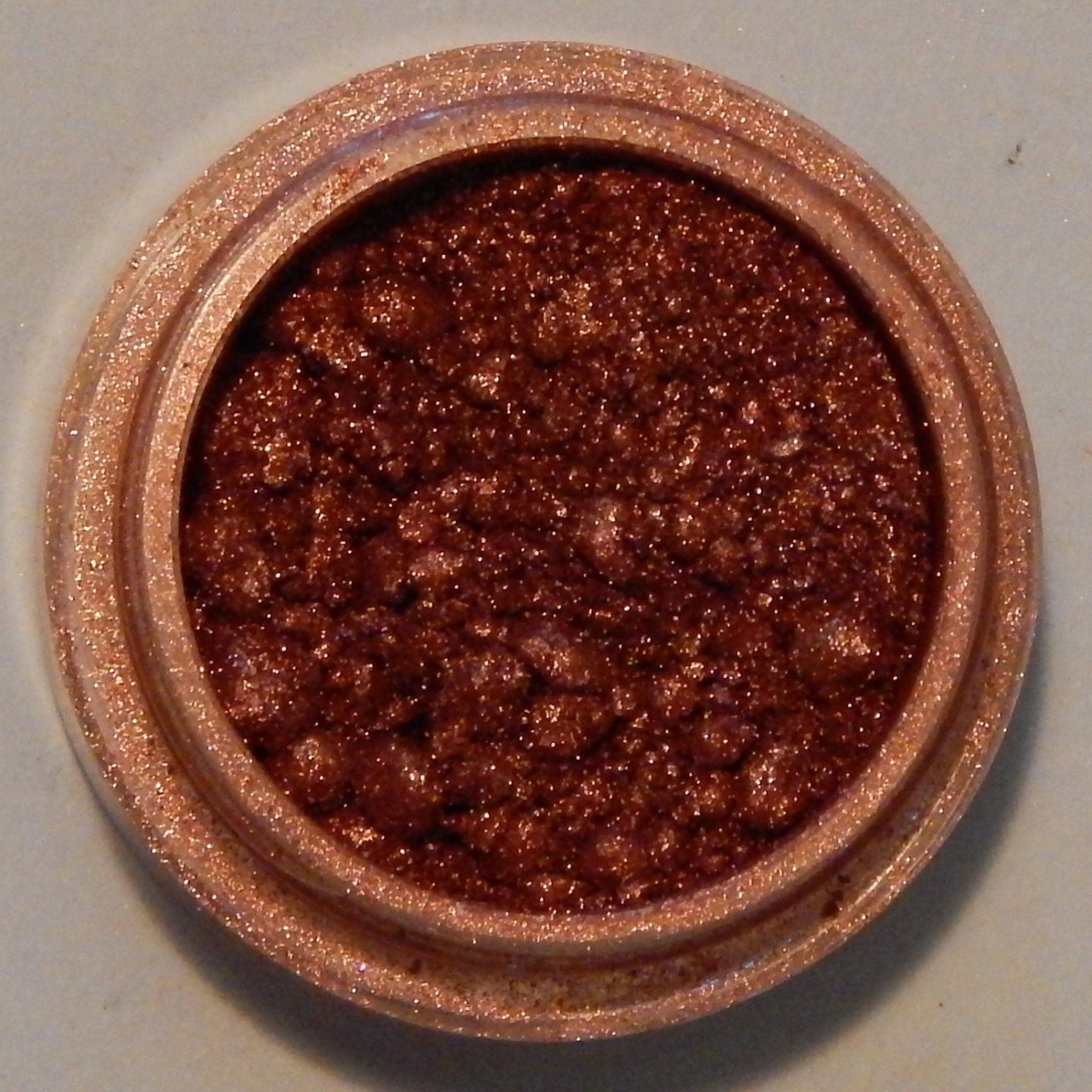Vibrant fiesta-orange mineral eyeshadow in compact with reflective gold case and embossed logo