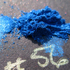 Side view of iridescent royal blue loose mineral eyeshadow with turquoise shimmer in a clear sifter jar