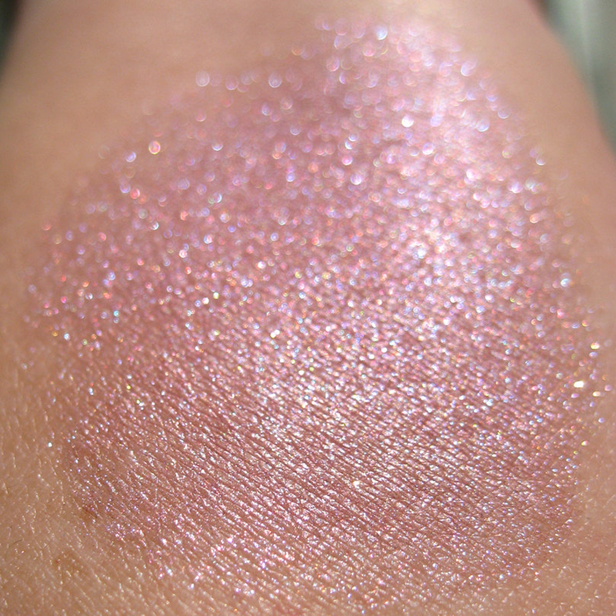 Pink glitter eyeshadow swatch on skin, showing shimmer and texture