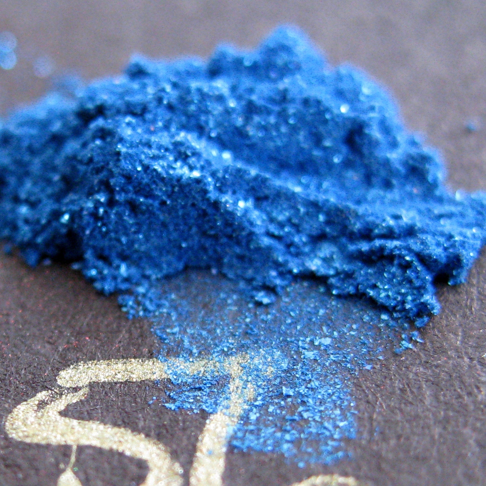 Vibrant royal blue loose mineral eyeshadow with iridescent turquoise shimmer and glitter in a clear jar