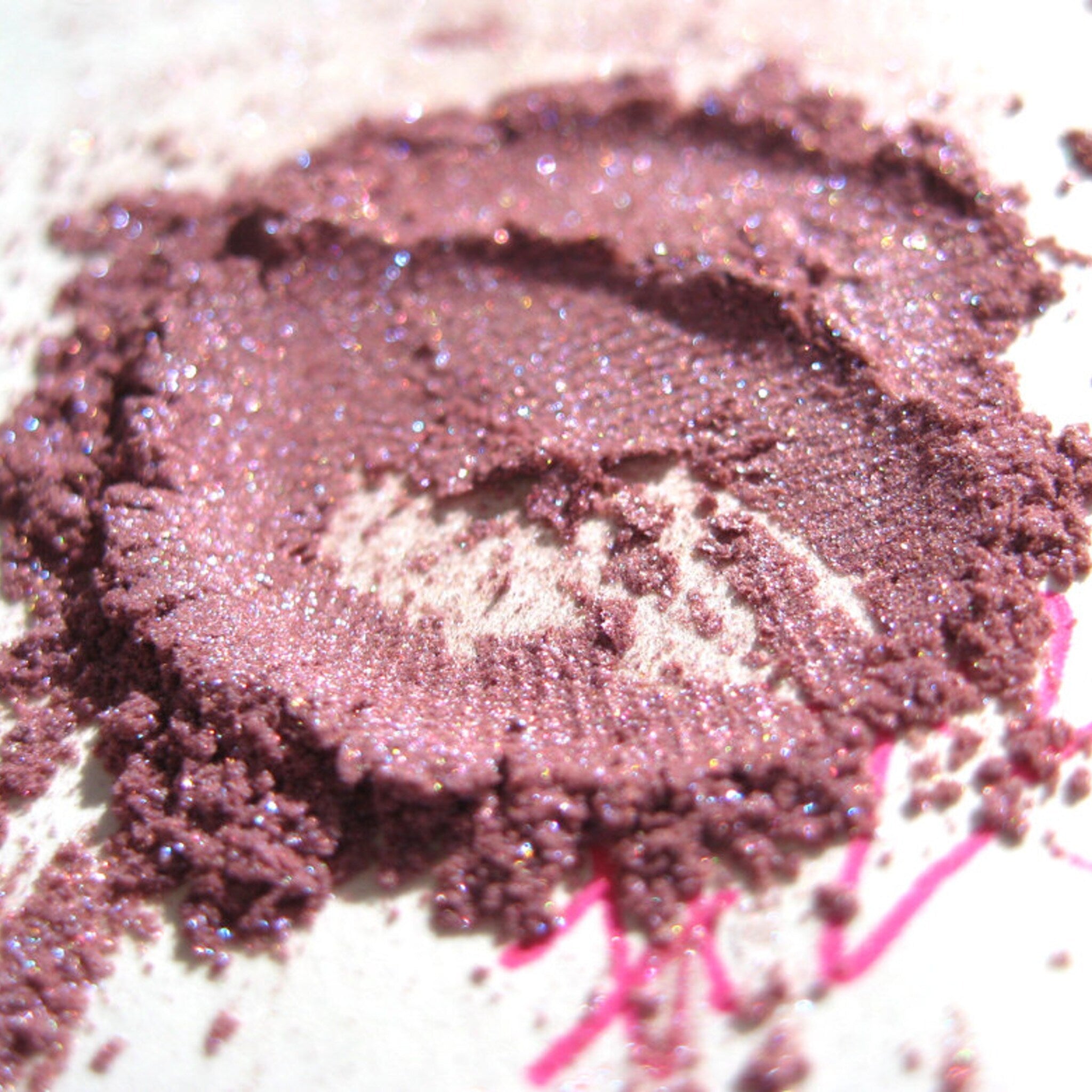 Eye shadow powder in mauve color with glitter particles on white surface