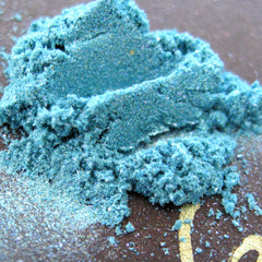 Turquoise blue loose mineral eyeshadow with teal, iridescent aqua, and purple shimmer in a small open jar