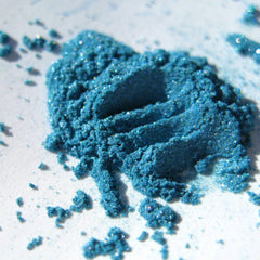 Close-up of iridescent turquoise blue loose eyeshadow with teal, aqua, and purple shimmer particles