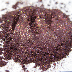 Close-up of warm metallic purple eyeshadow with iridescent copper shimmer and glitter particles catching light