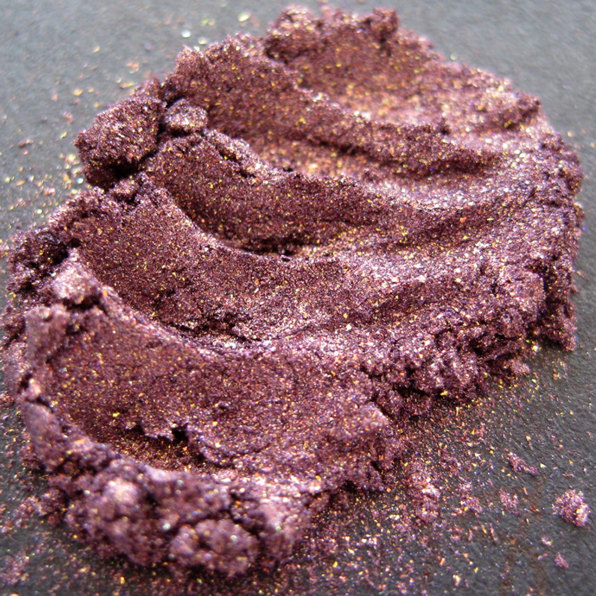 Open compact showing warm metallic purple eyeshadow with copper shimmer and glitter accents
