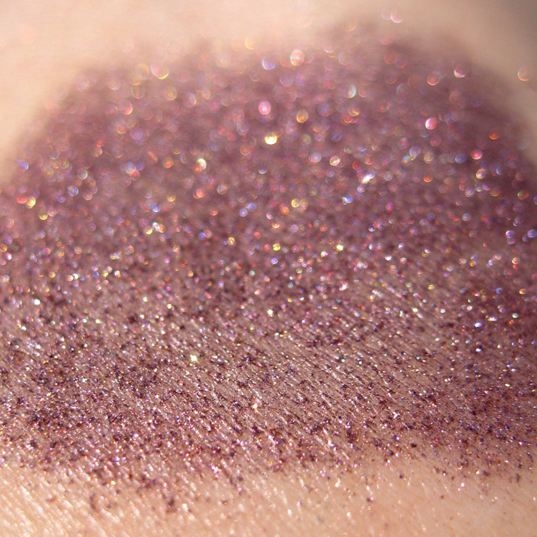 Side view of warm metallic purple eyeshadow with iridescent copper shimmer and glitter particles catching light