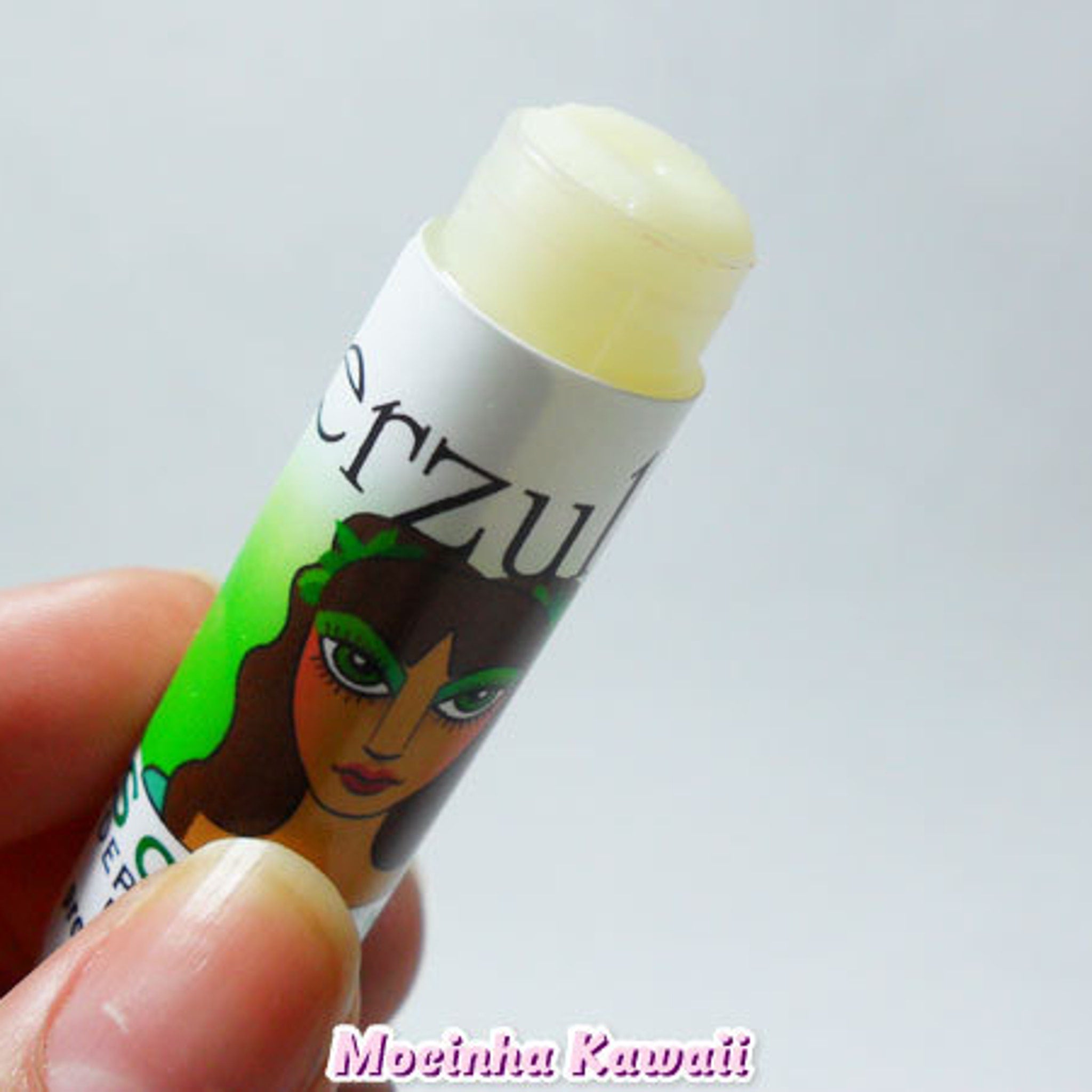 Lip balm tube with green and white design, "erzul" text, and yellow balm visible