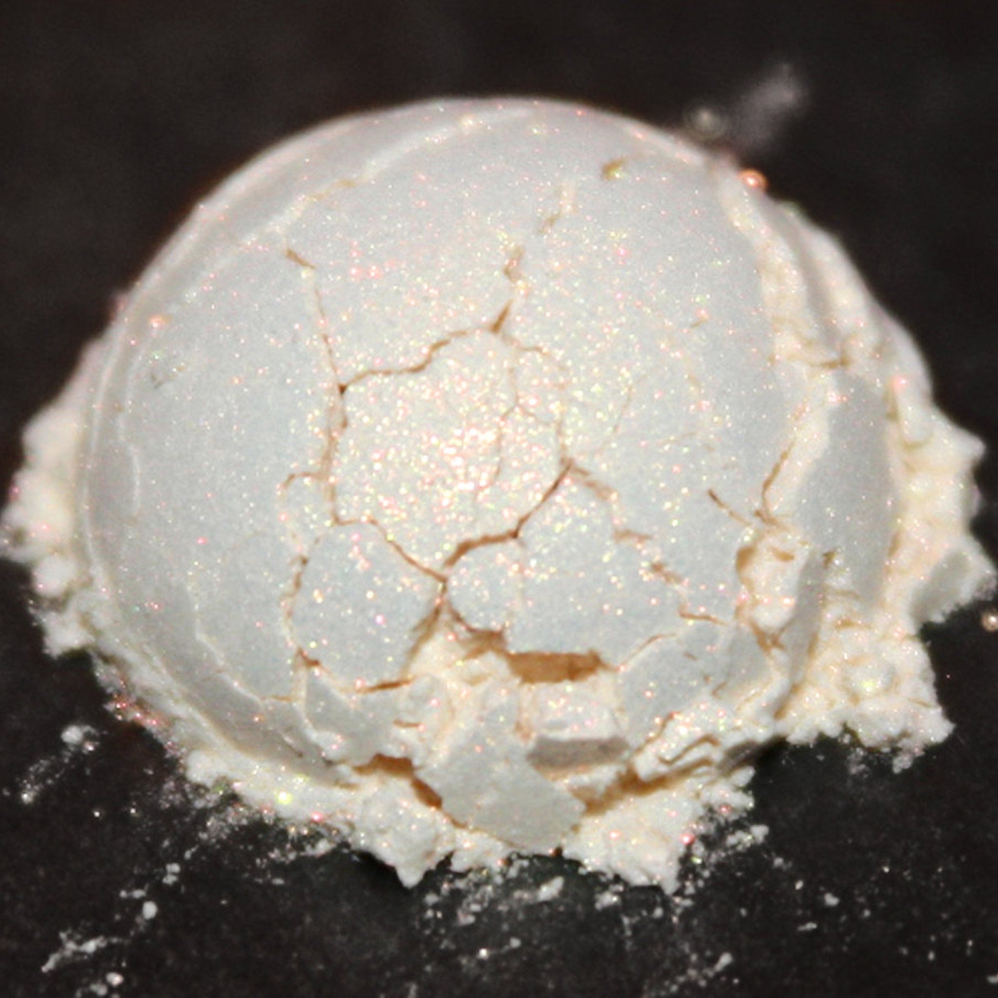 Side view of loose orange stardust shimmer eyeshadow with iridescent sparkle in clear jar