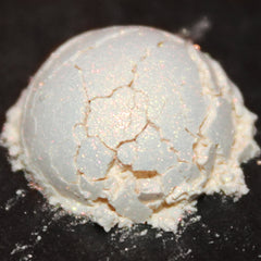 Side view of loose orange stardust shimmer eyeshadow with iridescent sparkle in clear jar