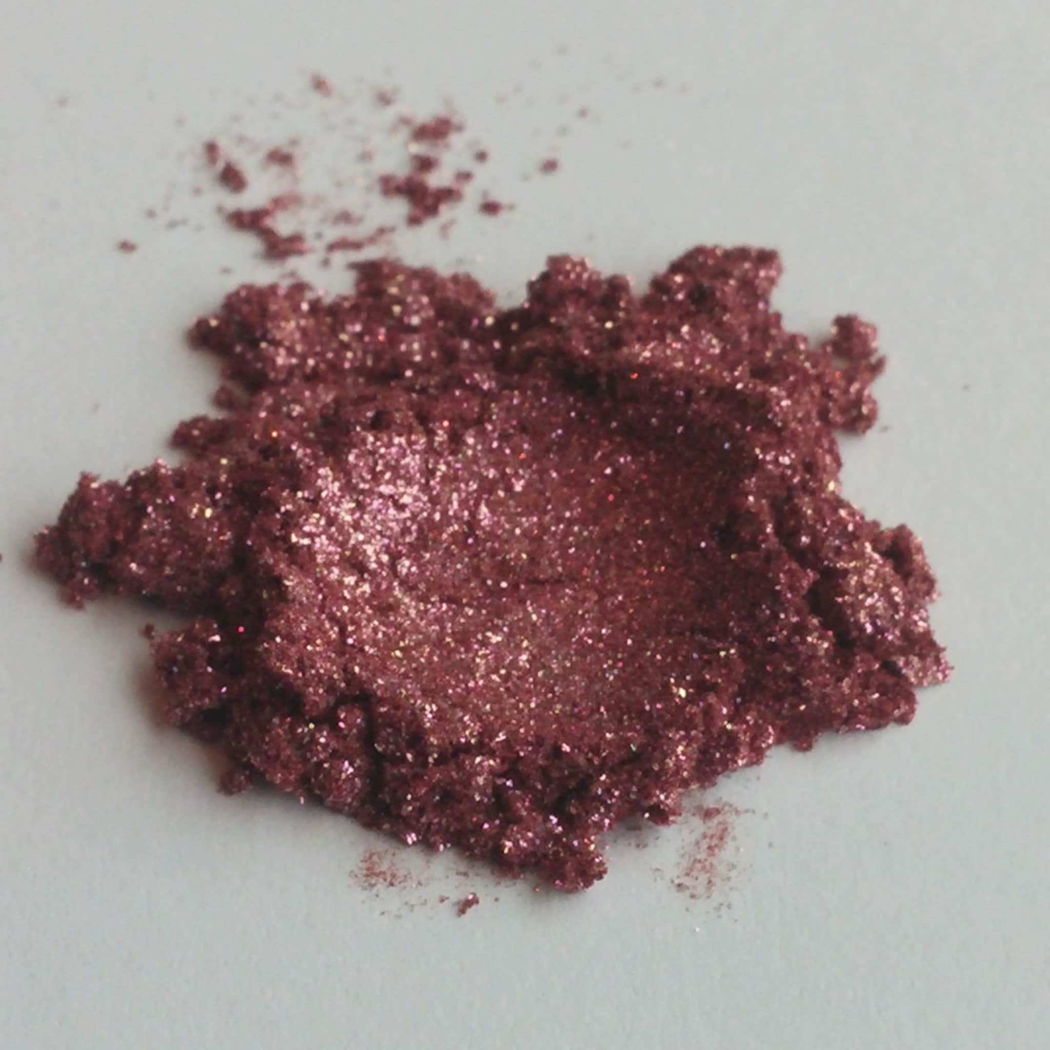 Loose eyeshadow powder in burgundy with sparkly glitter particles on white surface