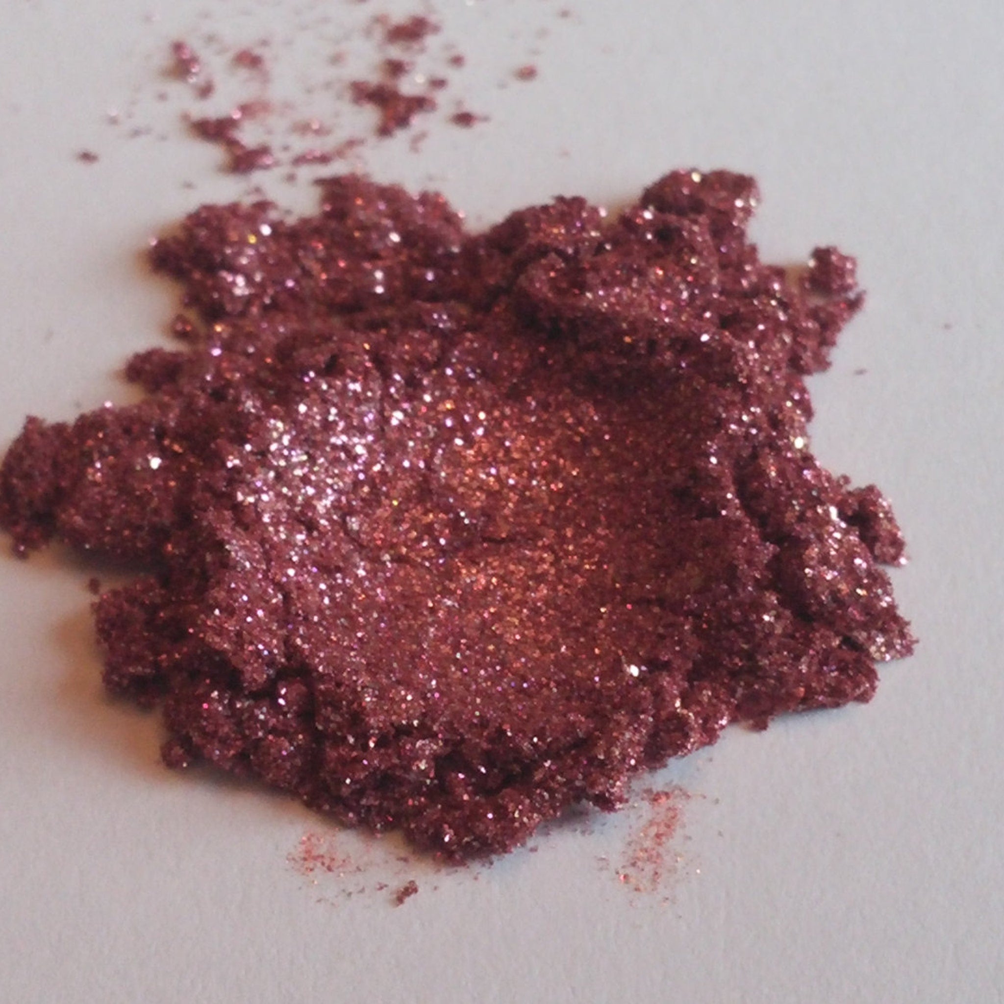 Eye shadow, burgundy mineral powder with glitter, close-up view on white surface
