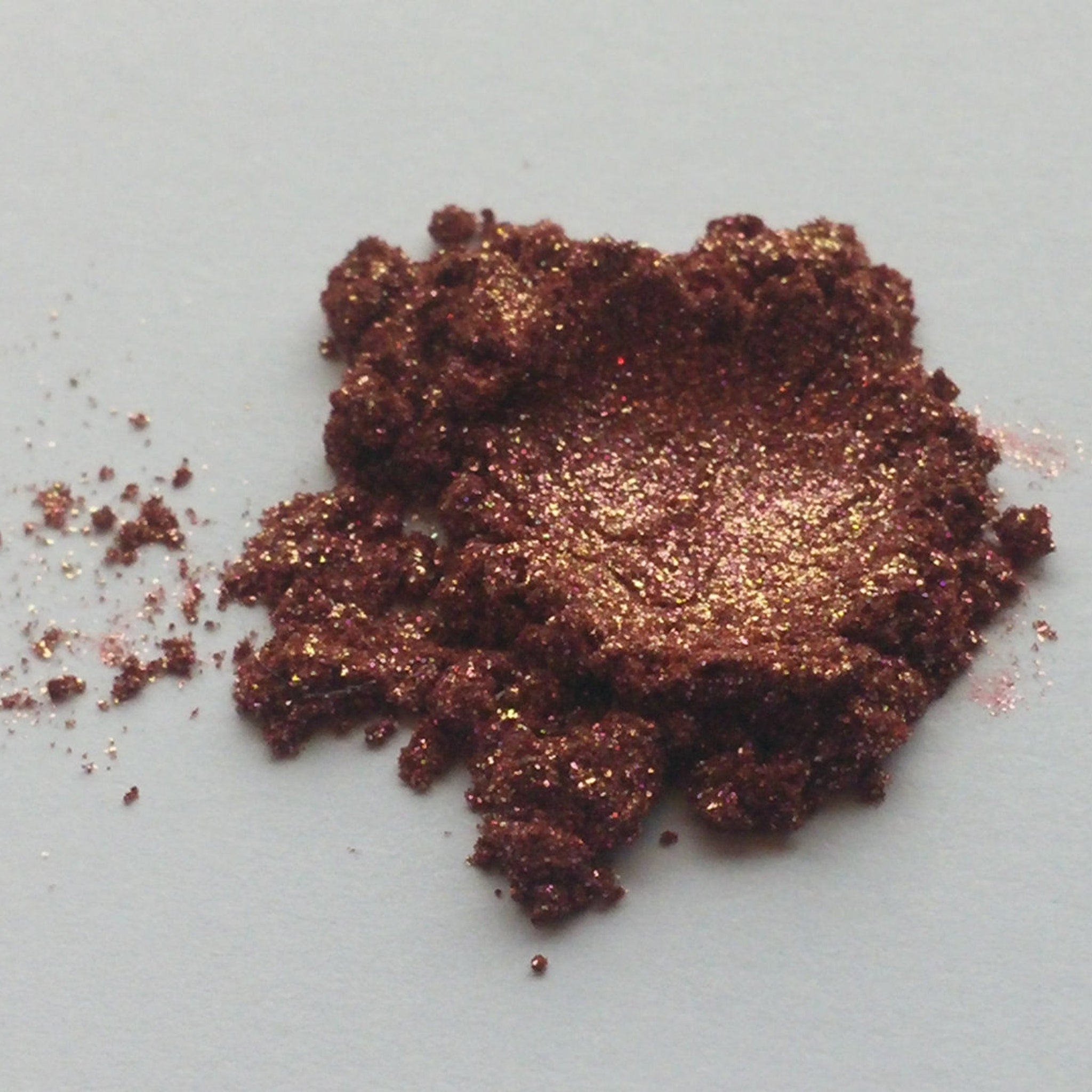 Eyeshadow powder, dark brown with gold shimmer and glitter, close-up view
