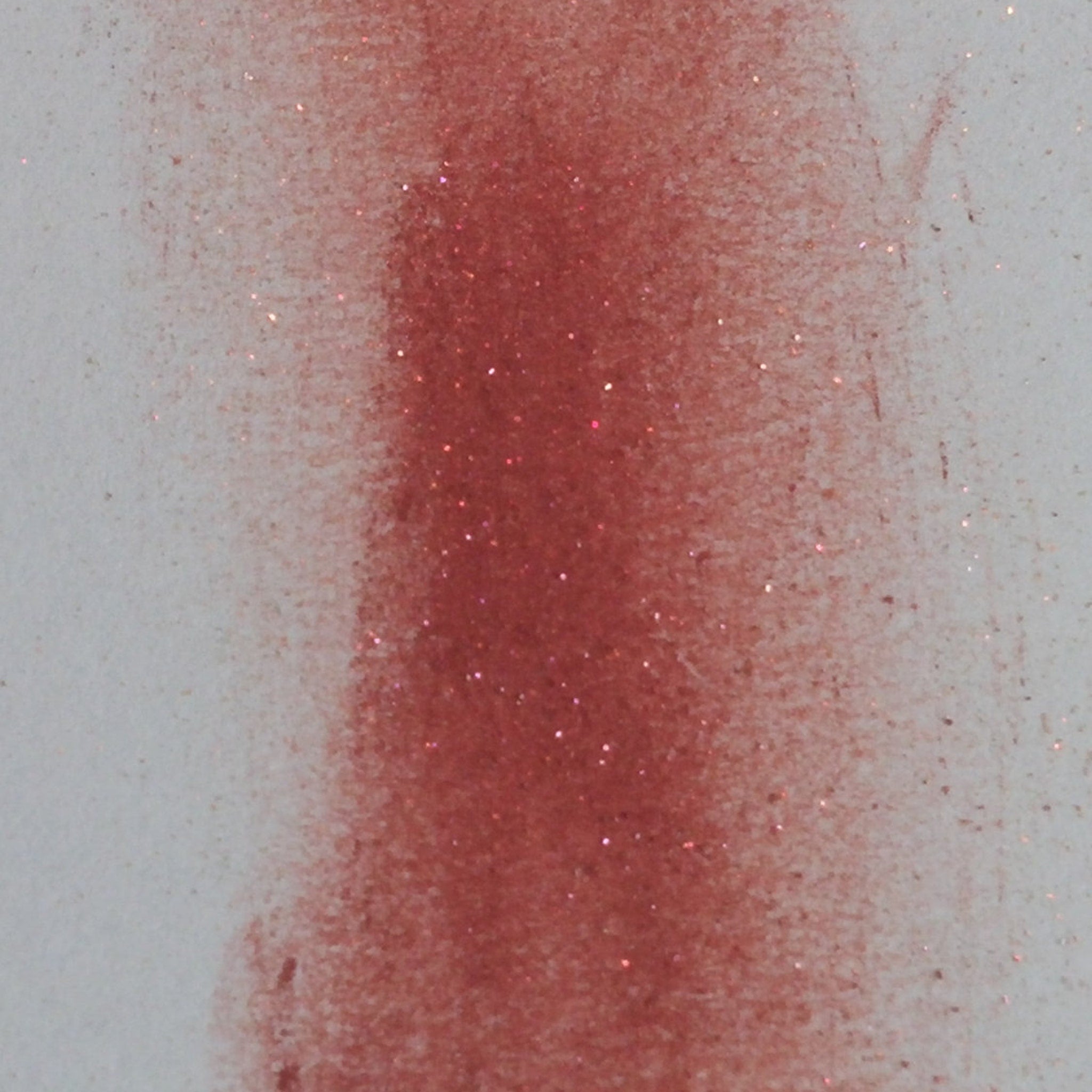 Red glittery pigment on white background with texture and sparkle