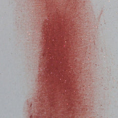 Red glittery pigment on white background with texture and sparkle
