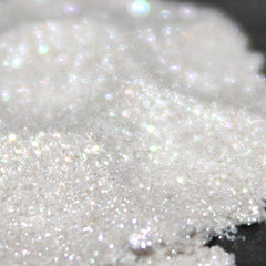 Side view of translucent white loose powder eyeshadow with sparkling flecks in a clear sifter jar