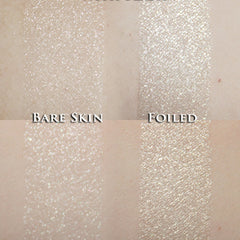 Hand applying loose white sparkle eyeshadow with brush, creating a shimmering highlight on eyelid