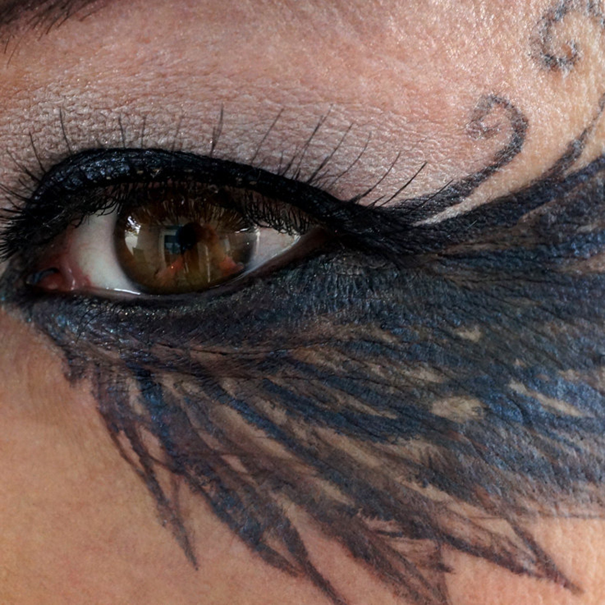 Close-up of loose iridescent gunmetal shimmer powder spilling from jar, showcasing metallic black pigment texture