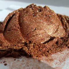Close-up of bronze and golden mineral eye shadow with shimmering flecks in compact palette