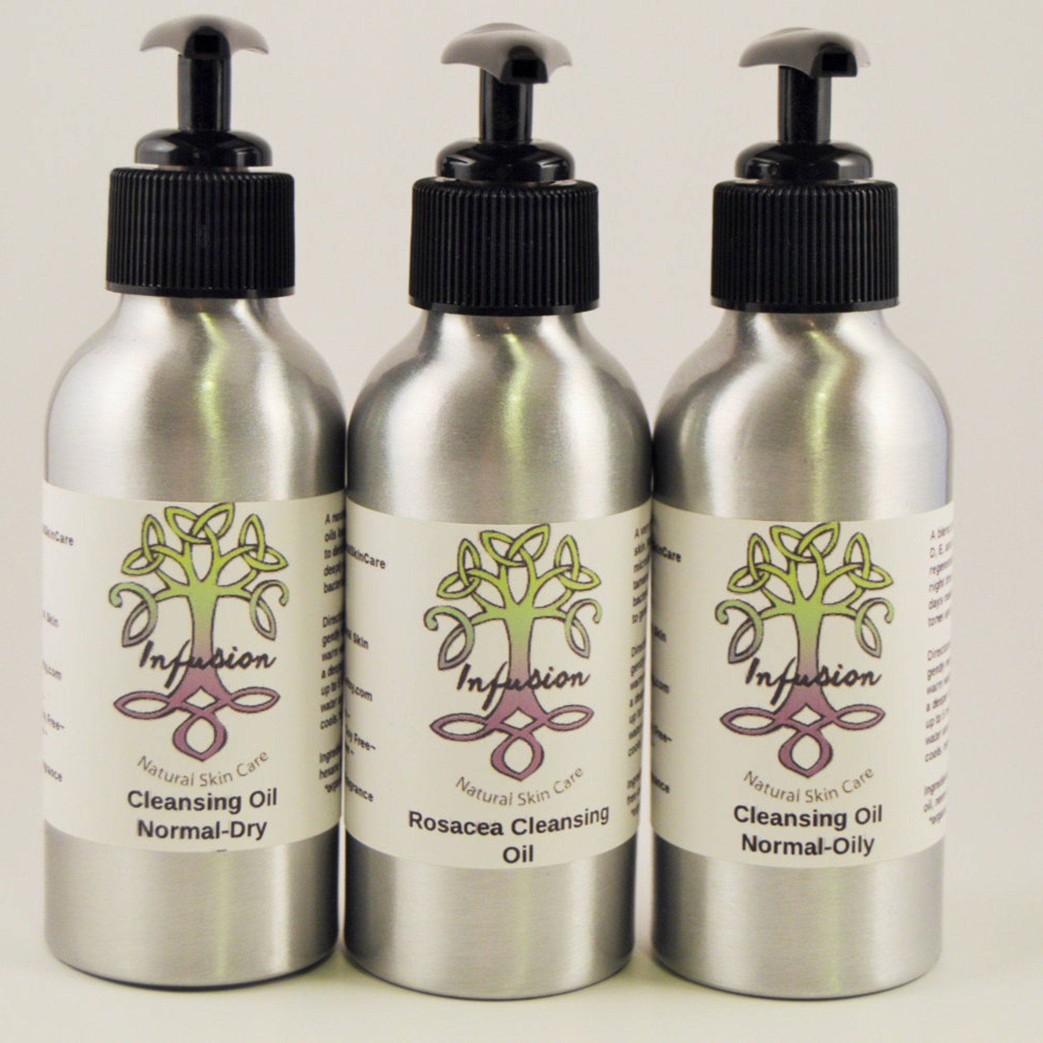 Cleansing oil bottles with black pump tops and silver metal bodies, Infusion brand visible