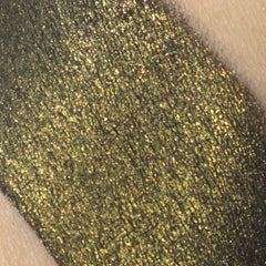 Close-up of fingertips applying black eyeshadow with gold shimmer to eyelid crease