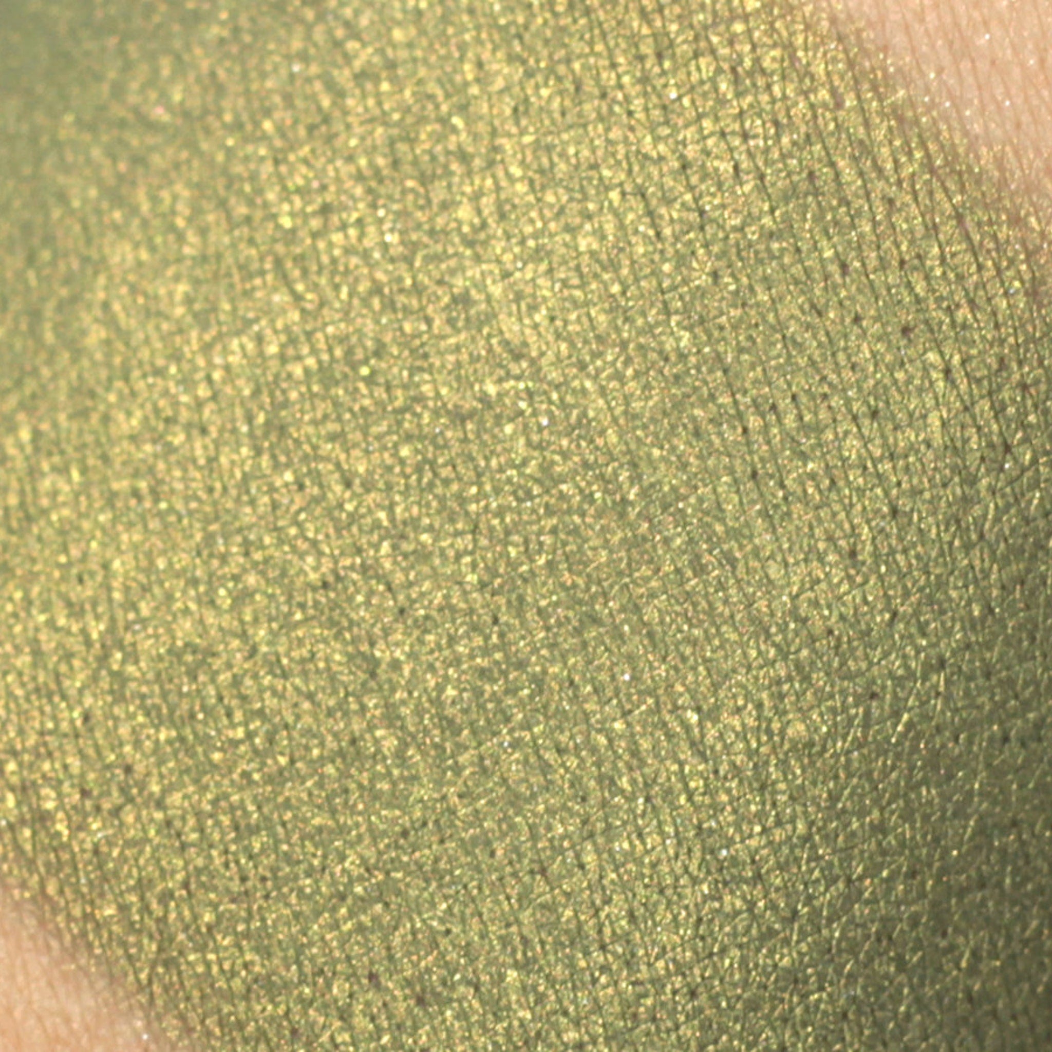 Green eyeshadow swatch with shimmery finish and crosshatch pattern on skin