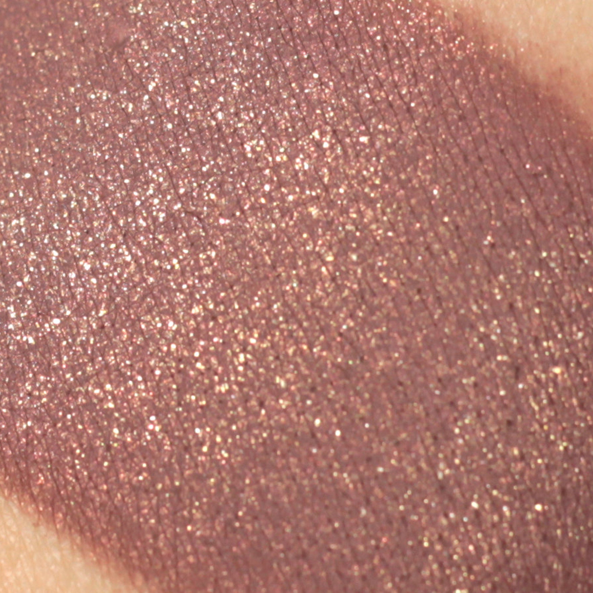 Eyeshadow swatch with shimmering mauve color and textured surface on skin