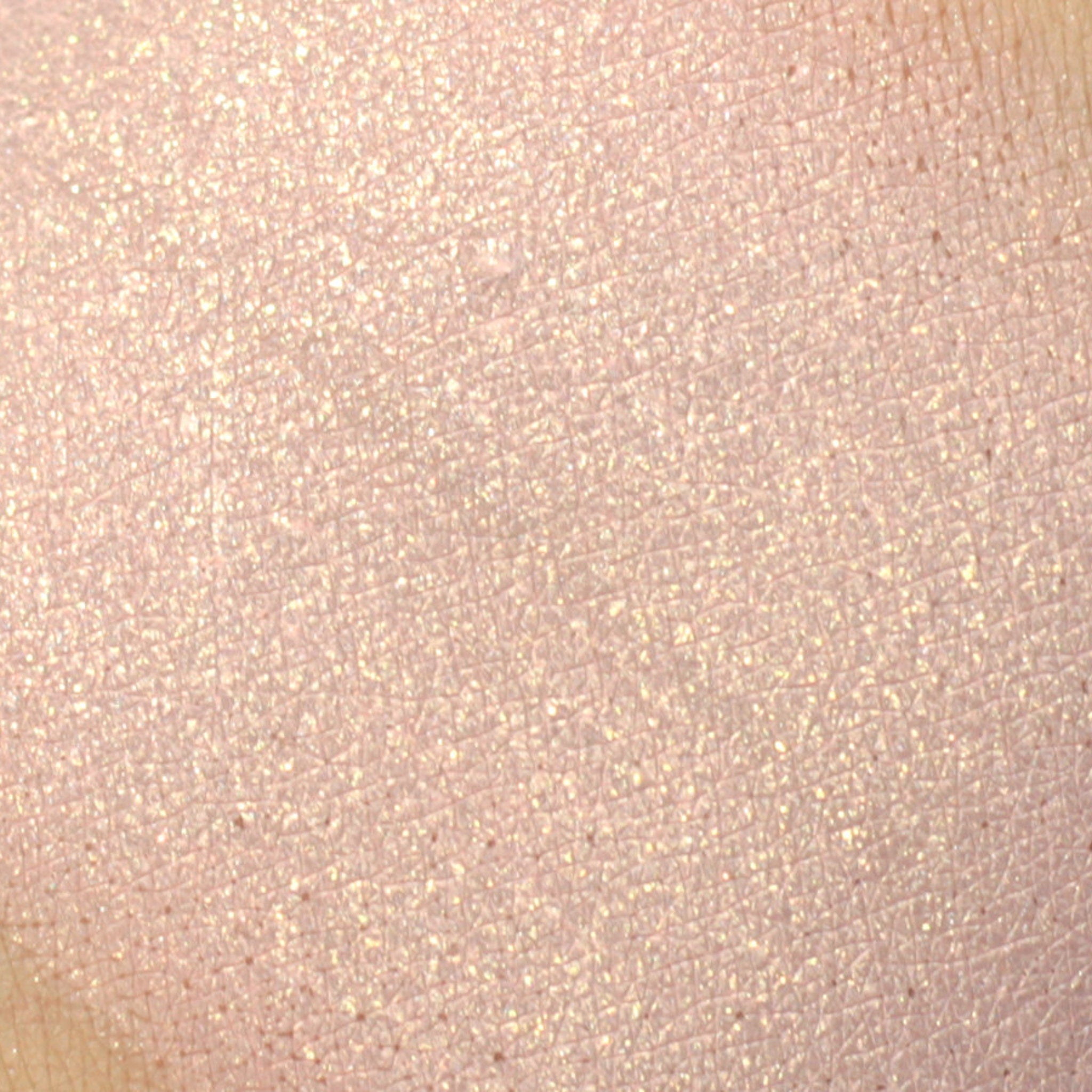 Woman applying light golden pink vegan mineral eyeshadow with fingertip to eyelid
