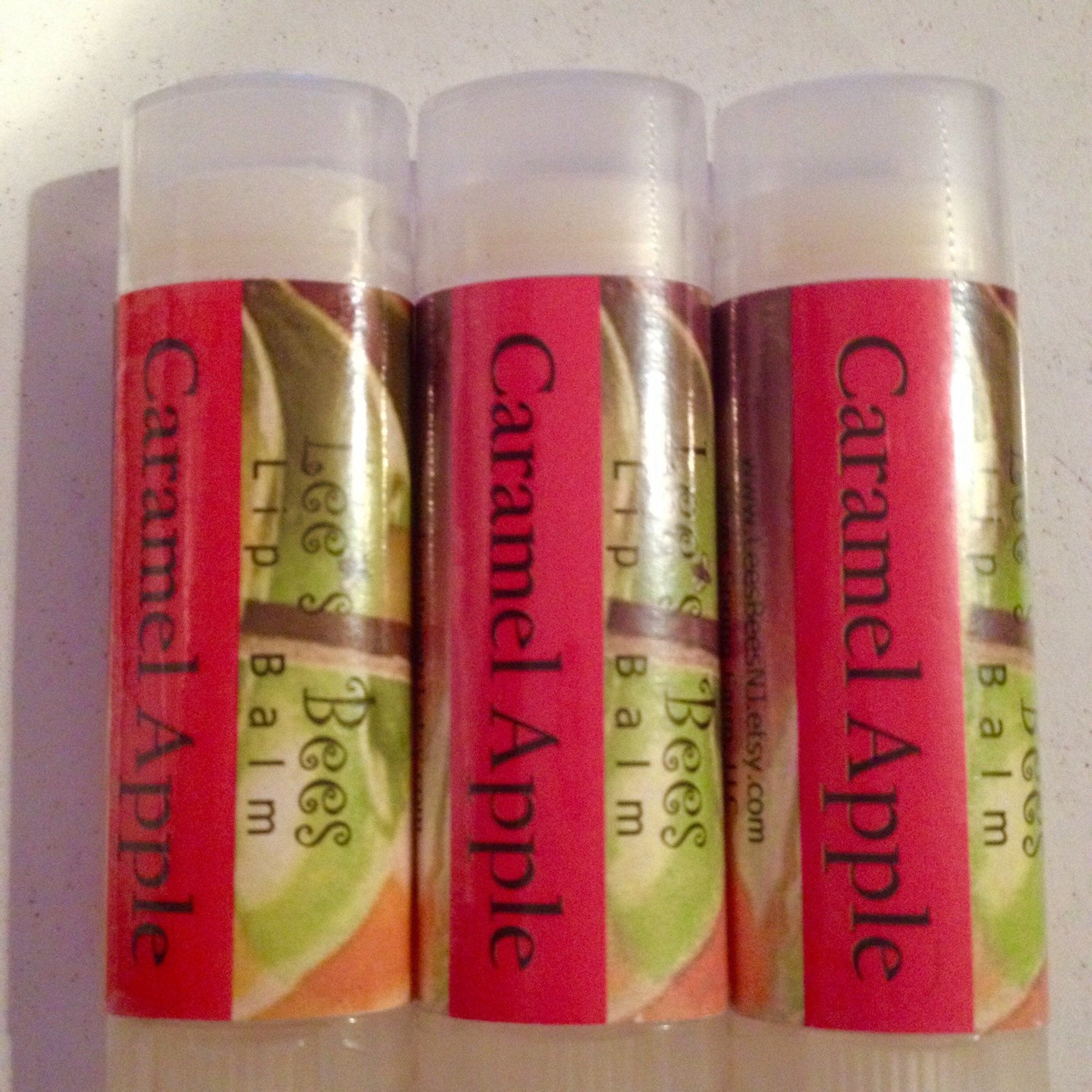 Lip balm tubes with red labels, clear caps, and "Caramel Apple" text