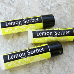Lip balm tubes with black, yellow and white labels, "Lemon Sorbet" text, moisturizing balm use