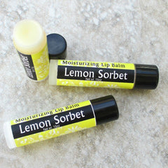 Lip balm tubes with yellow, black, and white labels, "Lemon Sorbet" text, and black caps