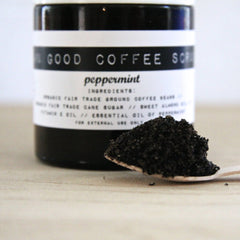 Coffee scrub in black jar with white label, peppermint ingredients, and wooden spoon