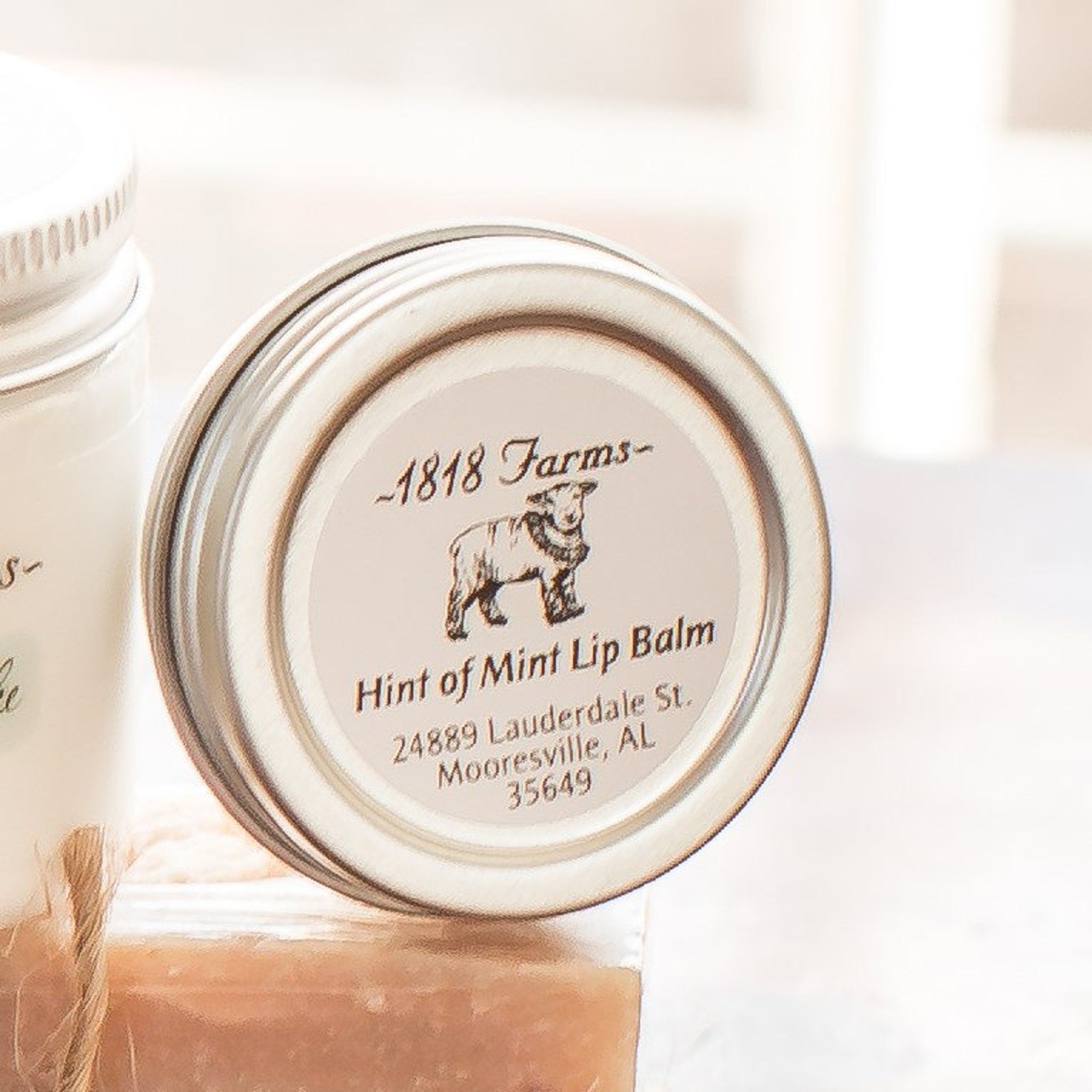 Lip balm tin with silver lid, white label, and 1818 Farms text and logo