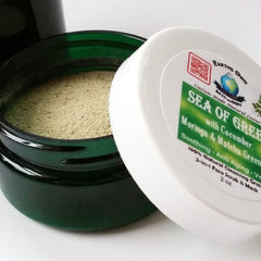 Facial cleanser jar with green powder, dark green glass, and white lid with Earth's Own text