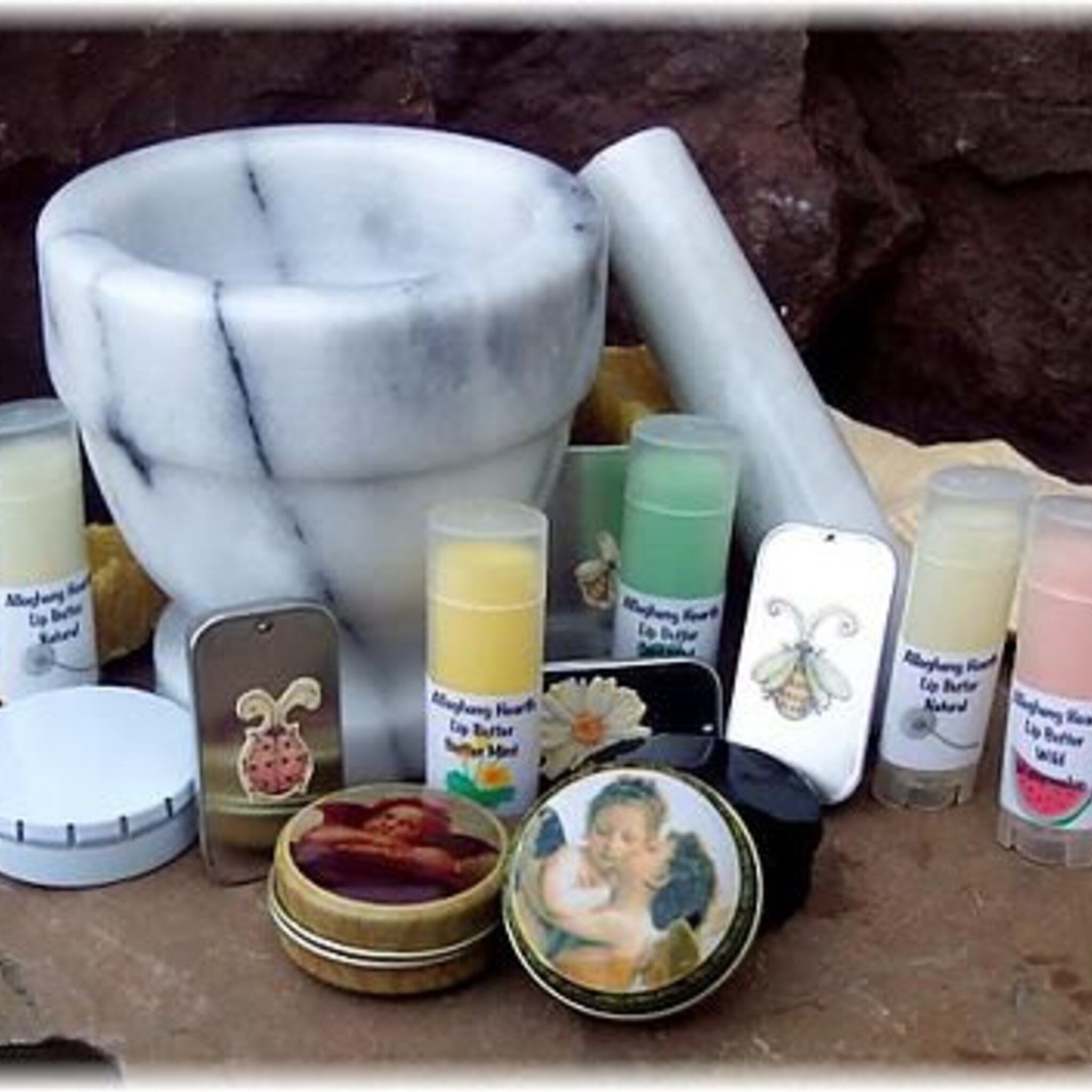 Lip balm tubes with white labels, various colors, and painted metal tins with images