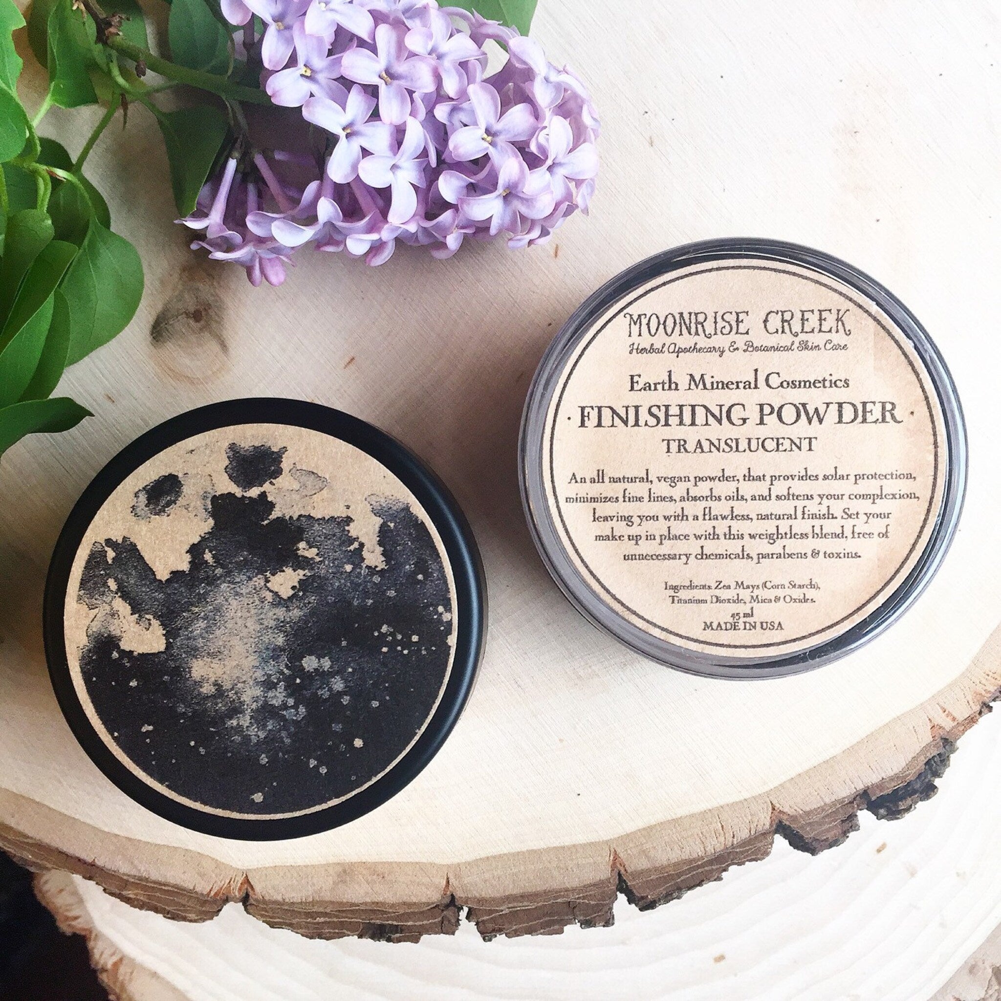Finishing powder in black and clear containers, with Moonrise Creek text on label, on wood surface