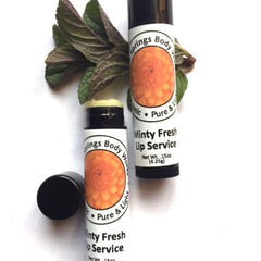 Lip balm tubes with orange floral label and black cap, "Minty Fresh Lip Service" with green leaves