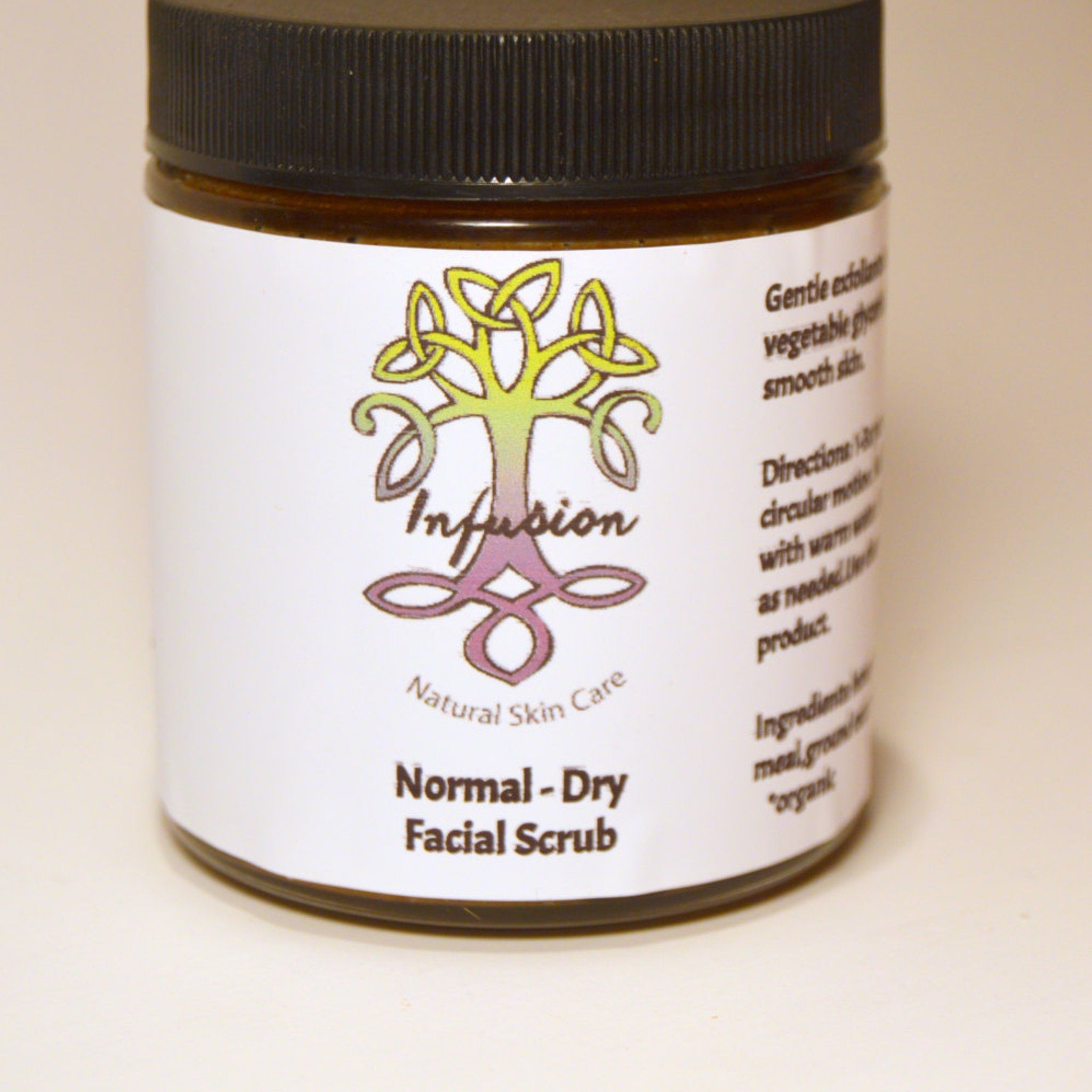 Facial scrub jar with black lid, white label, and Infusion Natural Skin Care text