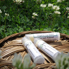 Lip balm tubes with white labels, clear caps, and text in a wicker basket with flowers